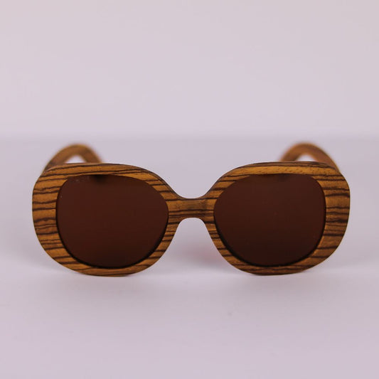 Vista frontal de las gafas FLORA KALO de Insolent donde se aprecia la suavidad de formas y el gran formato de su montura  en madera zebrano color toffee